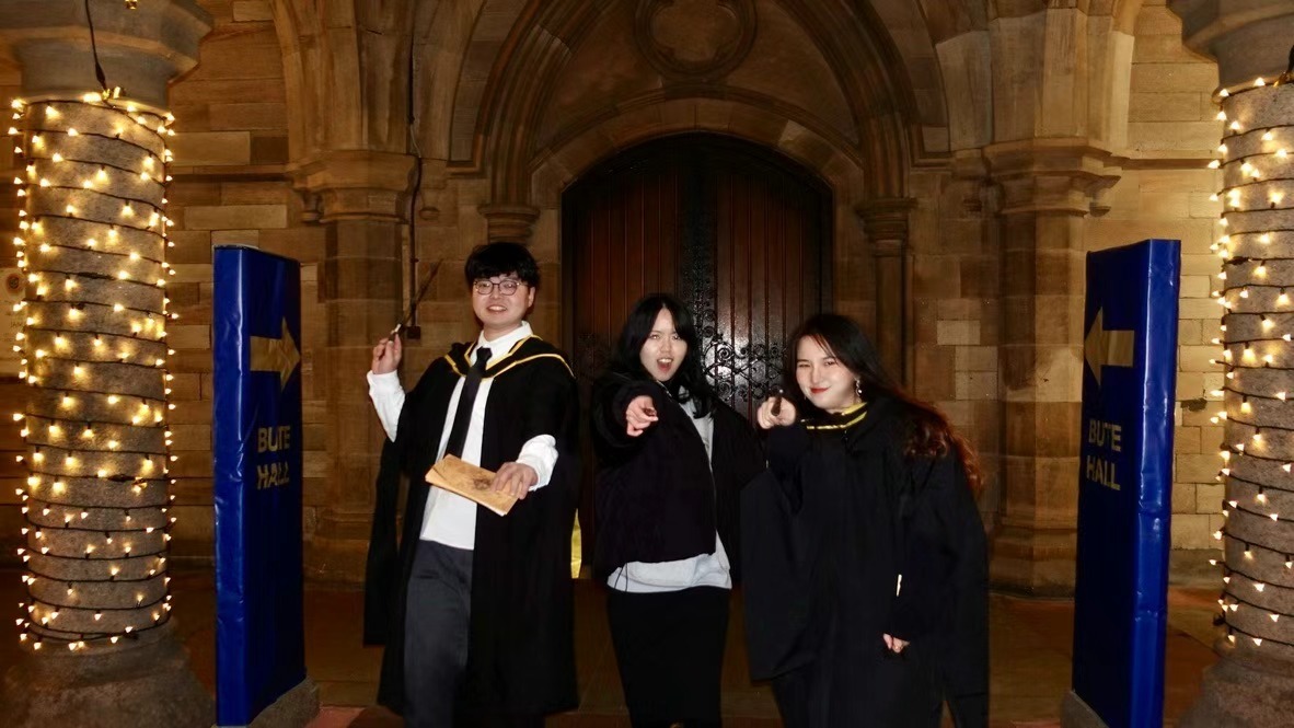 Xinyu Guan and two friends in graduation robes outside Bute Hall at night