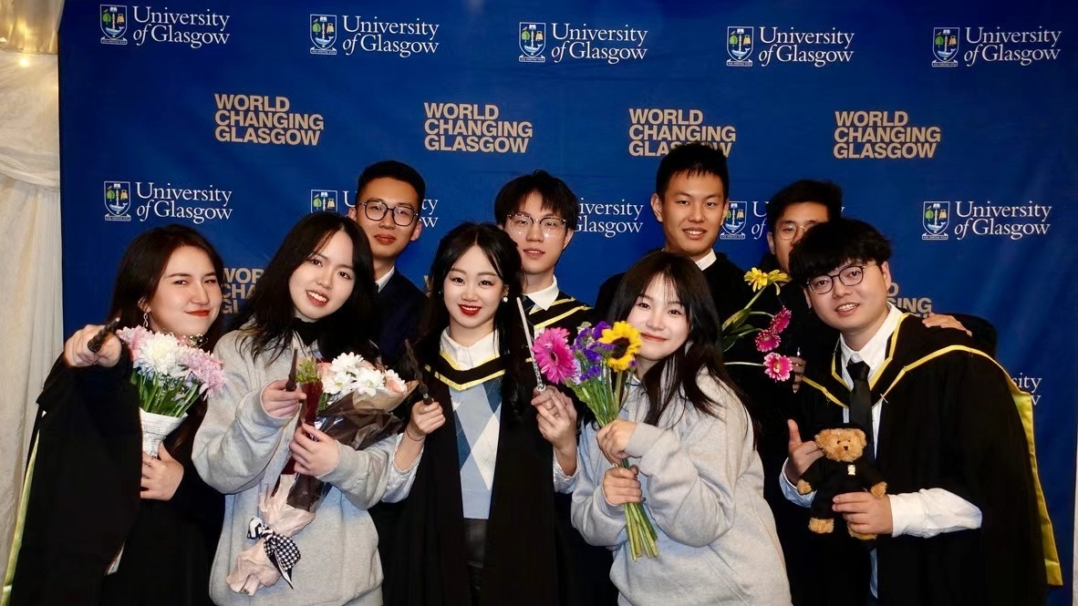 Xinyu Guan and friends posing with flowers at a University of Glasgow graduation celebration