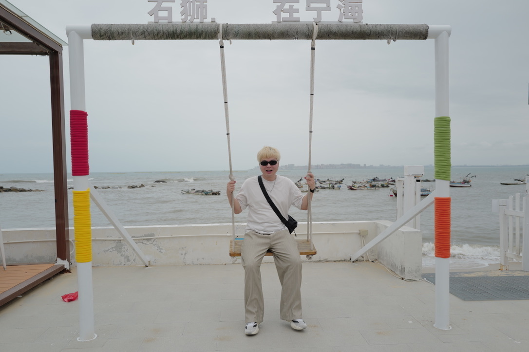 Xinyu Guan smiling on a seaside swing in Ninghai