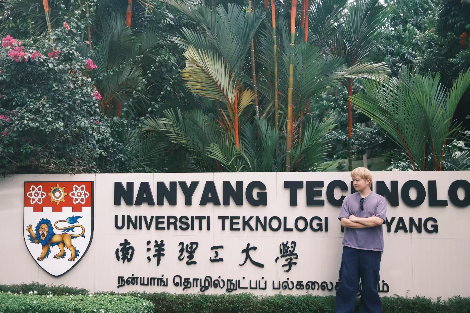 Xinyu Guan standing beside the Nanyang Technological University entrance sign