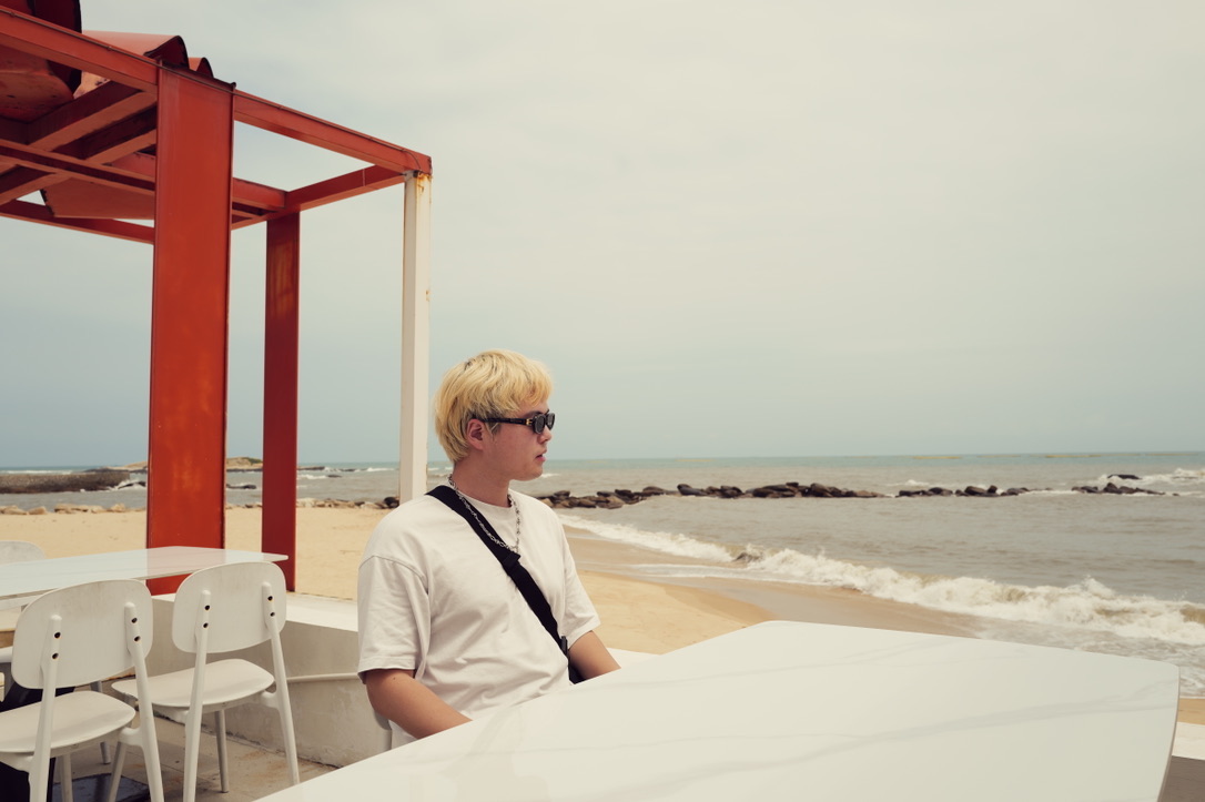 Xinyu Guan seated at a seaside cafe